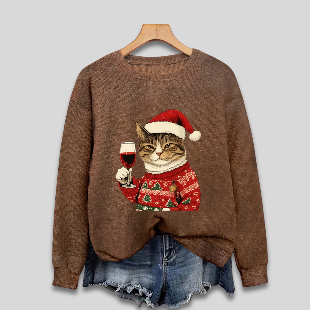 Pull marron avec motif de chat portant un bonnet de Noël, tenant un verre de vin, sur cintre. Vêtements d'hiver tendance, mode festive.