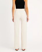 Femme portant un pantalon blanc ample, taille haute, avec un haut noir sans manches. Mode féminine élégante, tenue décontractée chic.