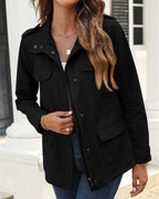 Femme portant une veste noire élégante avec poches, sur fond urbain. Mode automne, style décontracté chic, tendance vestimentaire féminine.