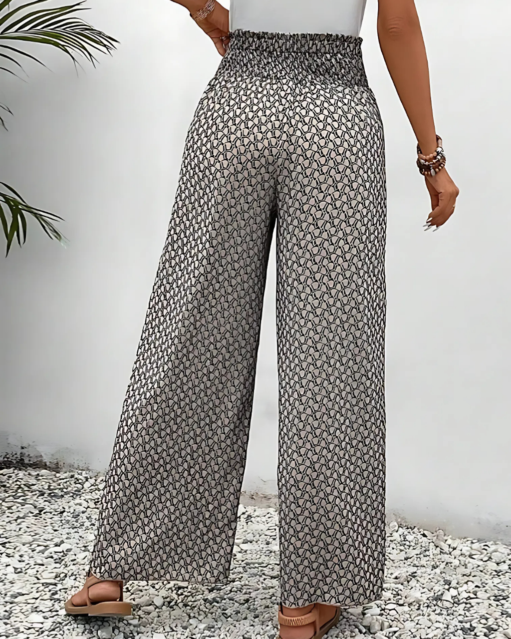 Pantalon large femme à motifs géométriques noirs et blancs, taille haute, porté avec un débardeur blanc. Mode estivale élégante et décontractée.