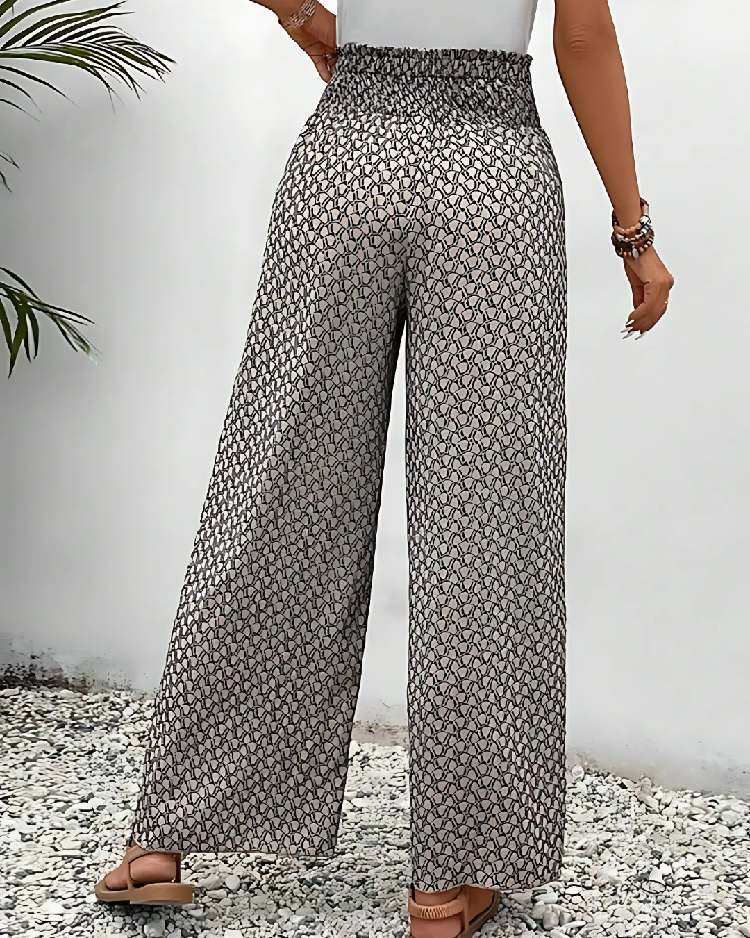 Pantalon large femme à motifs géométriques noirs et blancs, taille haute, porté avec un débardeur blanc. Mode estivale élégante et décontractée.