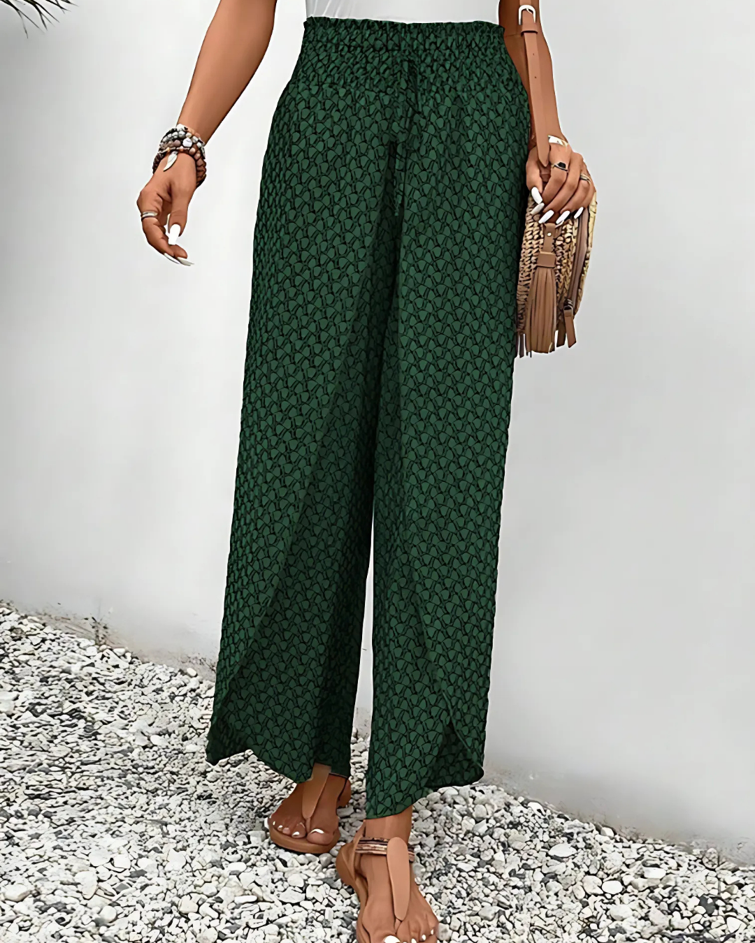 Pantalon large vert à motifs géométriques, porté par une femme avec sandales et sac à franges. Mode estivale, tenue décontractée élégante.