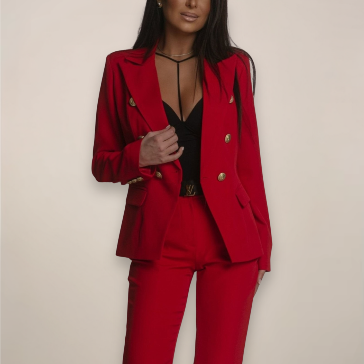 Femme en tailleur rouge élégant, veste à boutons dorés, top noir, pose confiante. Mode féminine, tenue professionnelle chic, style moderne.