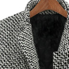 Manteau en laine noir et blanc à motif pied-de-poule, col tailleur, sur cintre en bois. Vêtement d'hiver élégant et tendance.