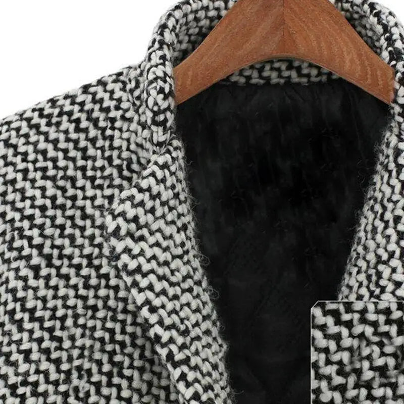 Manteau en laine noir et blanc à motif pied-de-poule, col tailleur, sur cintre en bois. Vêtement d'hiver élégant et tendance.