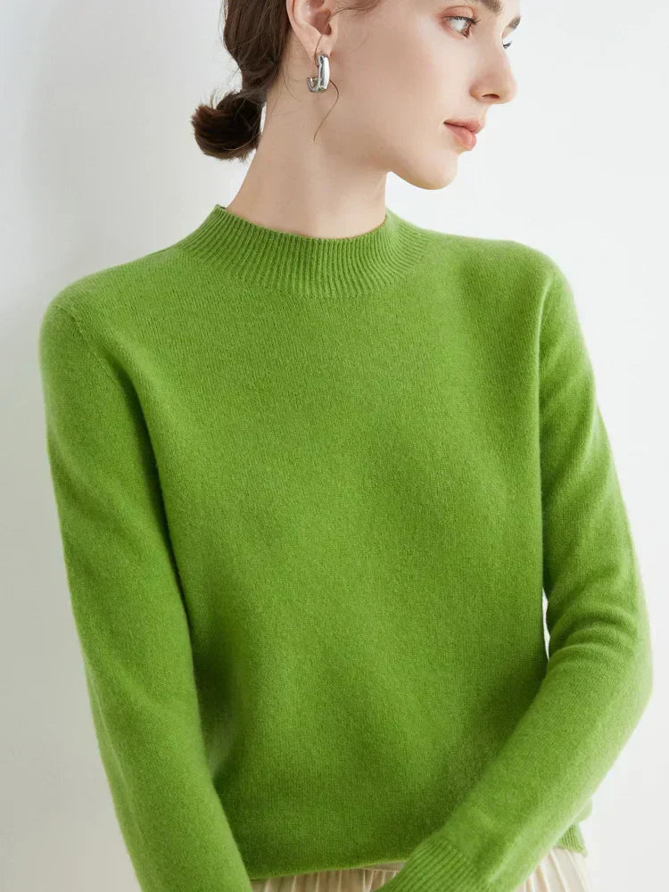 Femme portant un pull vert en cachemire, manches longues, col rond, posant de profil. Mode élégante, tendance automne-hiver, confort et style.