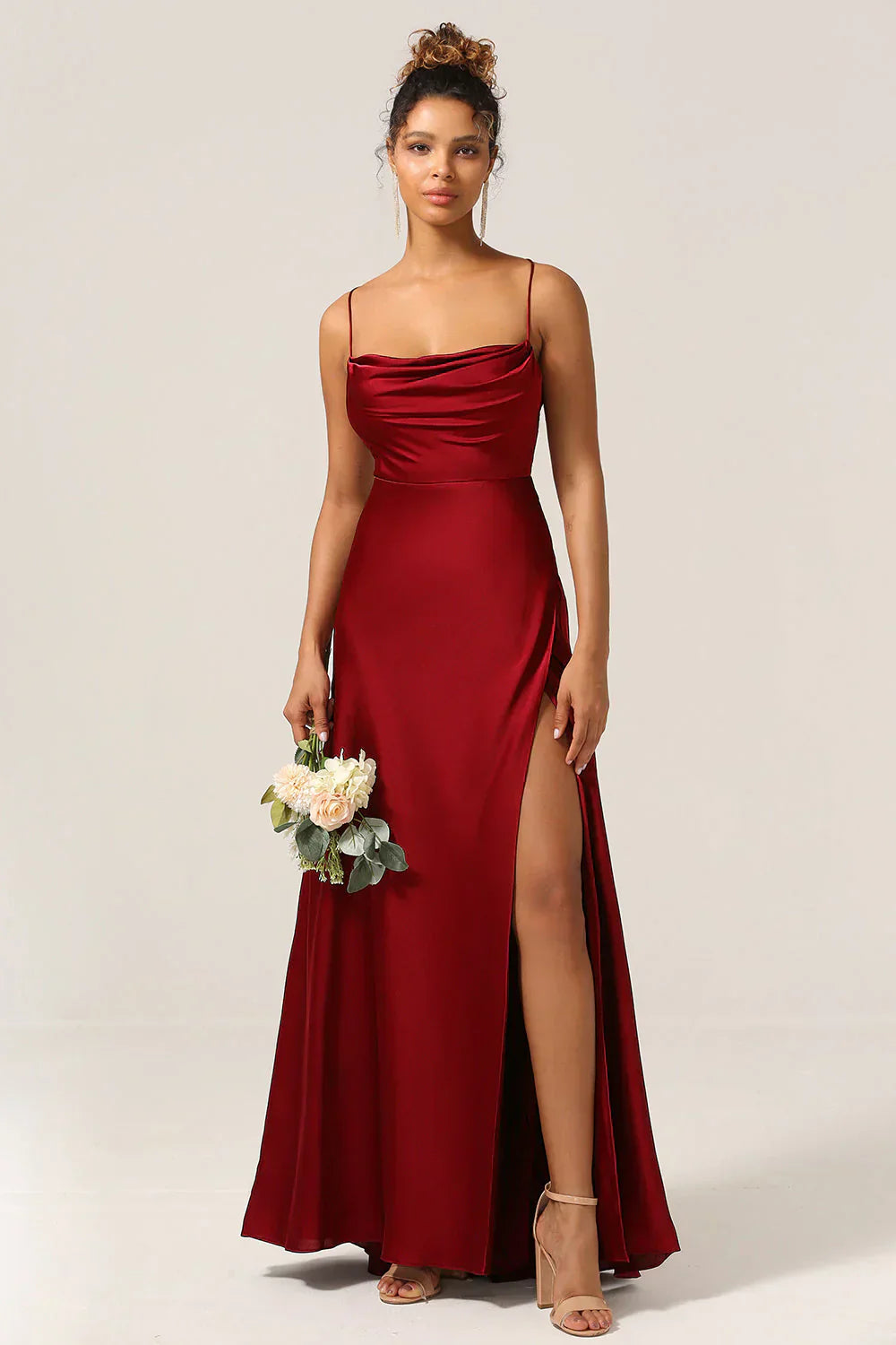 Robe de soirée rouge élégante avec fente haute, portée par une femme tenant un bouquet de fleurs blanches, style glamour et chic.