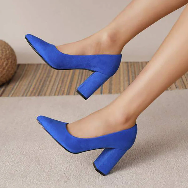 Escarpins bleus à talons blocs portés sur un tapis beige, mode féminine élégante, chaussures tendance pour femmes, style moderne et chic.