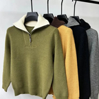 Cinq pulls en laine à col zippé, suspendus sur des cintres, dans des couleurs olive, jaune, marron, noir et gris. Mode automne-hiver tendance.
