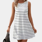 Robe d'été blanche à rayures noires, sans manches, portée par une femme tenant un sac noir. Mode féminine, style décontracté, tendance estivale.