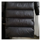 Doudoune longue noire en tissu matelassé, design moderne et élégant, idéale pour l'hiver. Vêtement chaud et tendance pour homme ou femme.