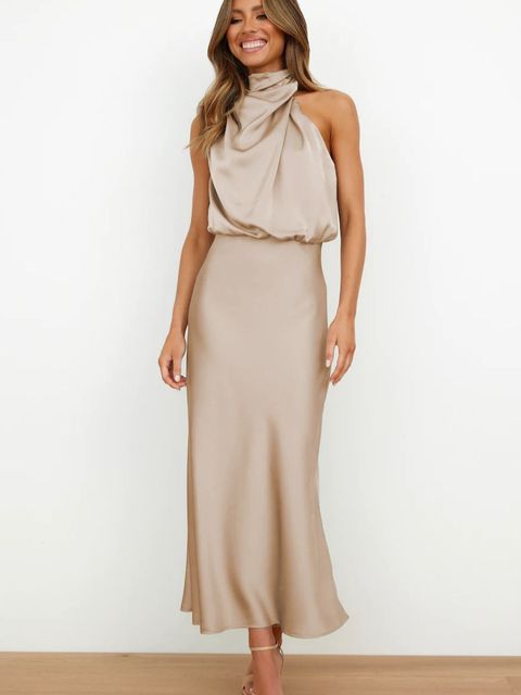 Robe longue beige élégante avec col drapé, portée par une femme souriante. Mode féminine chic, tenue de soirée tendance.