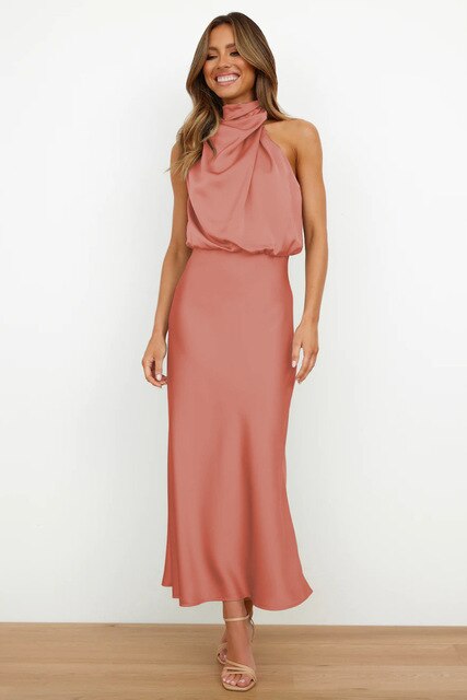 Robe longue rose saumon élégante, sans manches, avec col drapé, portée par une femme souriante. Mode féminine chic, tendance soirée.
