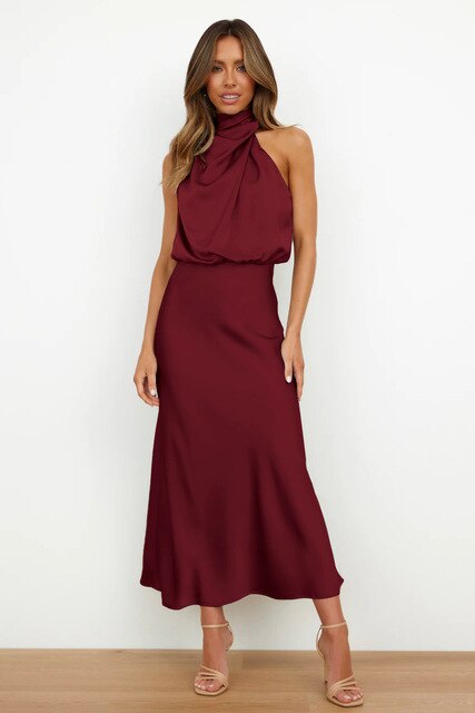Robe longue bordeaux élégante, sans manches, col drapé, portée par une femme sur fond blanc. Mode féminine chic, tendance soirée.