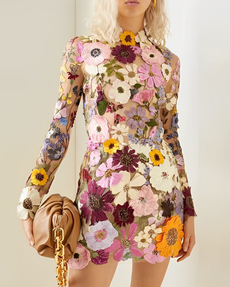 Robe florale transparente avec motifs de fleurs colorées, tenue par une femme blonde. Sac à main en cuir beige avec chaîne dorée. Mode élégante et tendance.