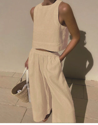 Femme en ensemble beige sans manches, pantalon ample, tenant un sac en osier. Mode estivale minimaliste, tenue décontractée chic.