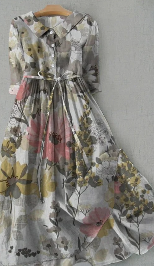 Robe longue fleurie vintage avec manches trois-quarts, col rond et ceinture à nouer, motifs floraux multicolores sur fond gris.