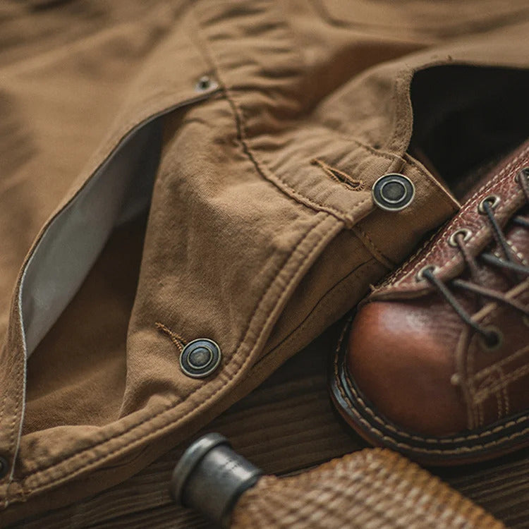 Pantalon en toile marron avec boutons pression, chaussure en cuir marron, style vintage, mode masculine, accessoires rétro, gros plan.