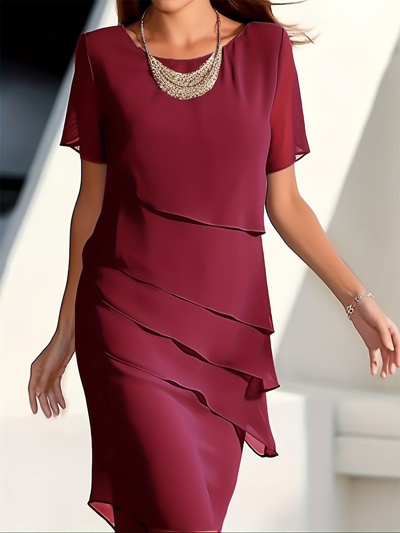Robe bordeaux élégante à volants superposés, portée par une femme, avec collier doré. Mode féminine chic, tenue de soirée sophistiquée.