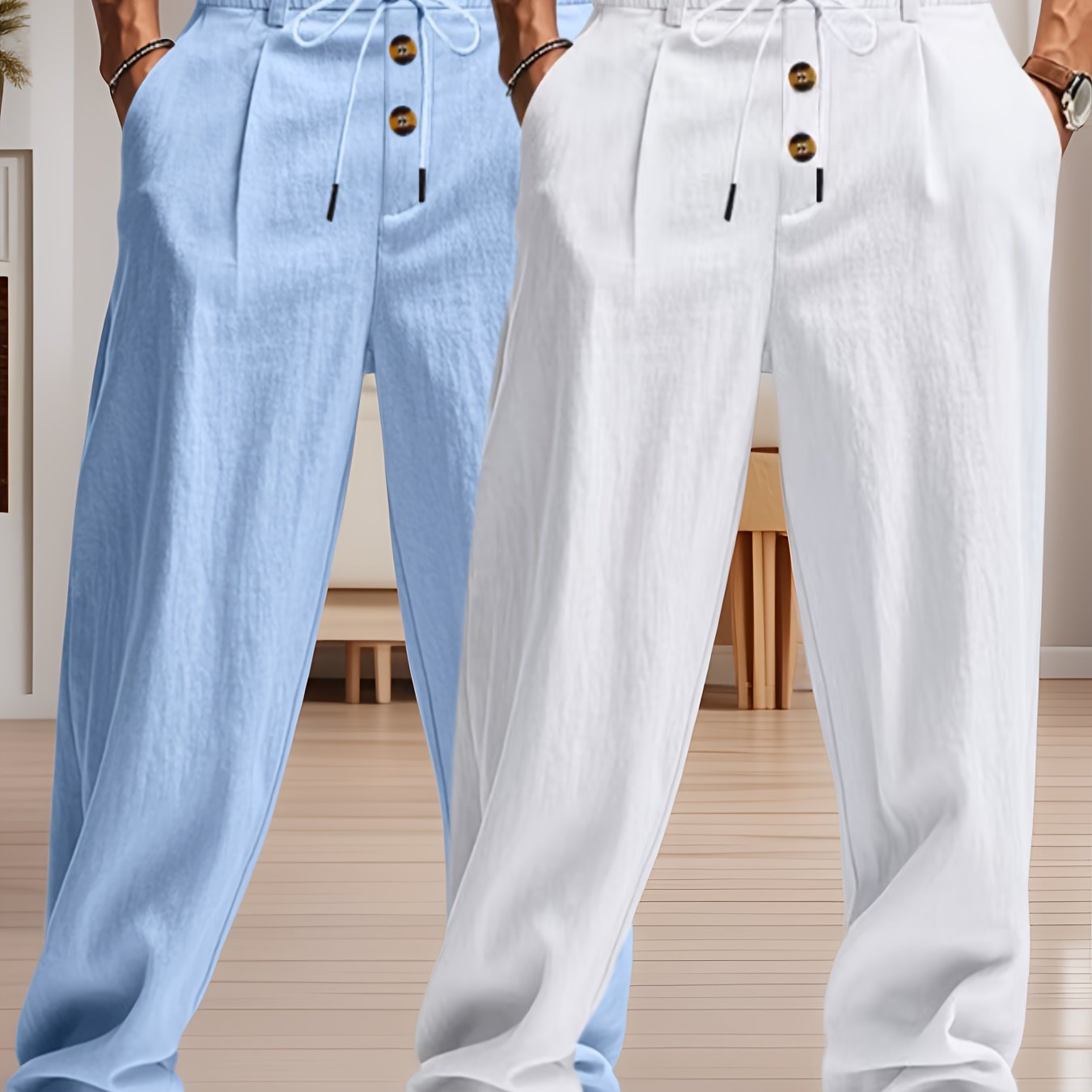 Deux pantalons en lin, l'un bleu clair et l'autre blanc, avec cordons et boutons en bois, posés dans un intérieur moderne et lumineux.