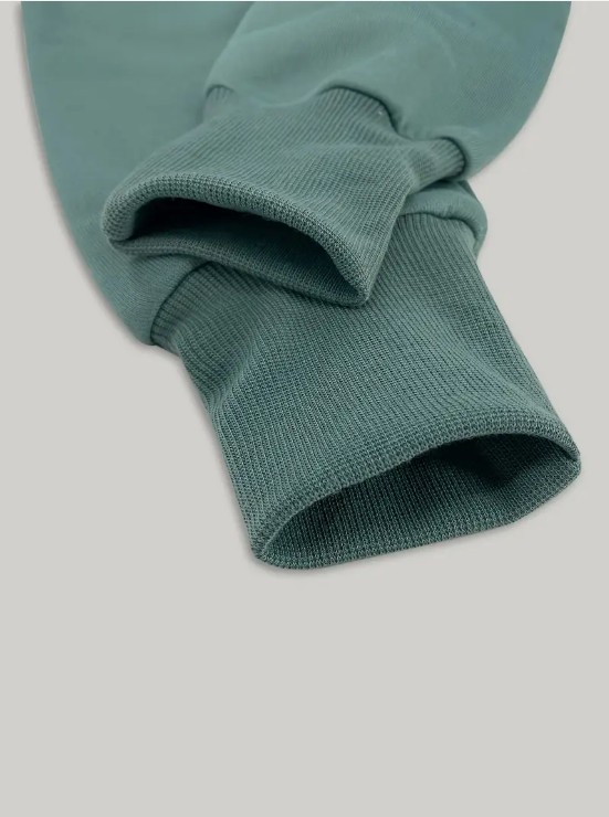 Manche de sweat-shirt vert en coton, gros plan sur les poignets côtelés. Mode décontractée, vêtement confortable, style moderne.