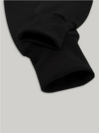 Manche de sweat-shirt noir en coton, gros plan sur le poignet côtelé. Mode décontractée, vêtement basique, style minimaliste.