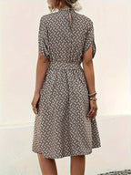 Robe mi-longue à motifs géométriques noirs et beiges, manches courtes, ceinture à nouer, style décontracté chic, vue de dos.