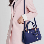 Femme en manteau rose portant un sac à main bleu élégant avec nœud décoratif, mode féminine chic, accessoires tendance, style automne-hiver.