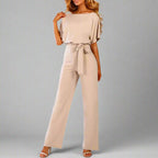 Combinaison beige élégante pour femme avec ceinture nouée, manches courtes, coupe ample, idéale pour mode chic et décontractée.