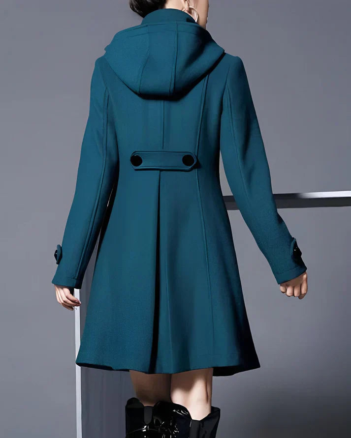 Manteau bleu femme avec capuche, boutons décoratifs noirs, manches longues, style élégant et moderne, mode automne-hiver.