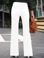 Femme en jean blanc évasé, tenant un sac à main marron, vue de dos. Mode urbaine, style décontracté, tendance automne.