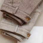Pantalons en tweed marron clair pliés, boutons en bois, motif chevrons, tissu élégant et texturé, mode automne-hiver, style classique et intemporel.