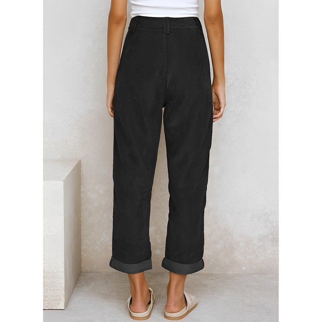 Femme portant un pantalon noir ample, taille haute, avec ourlets retroussés, vue de dos. Mode décontractée, tendance, style estival.