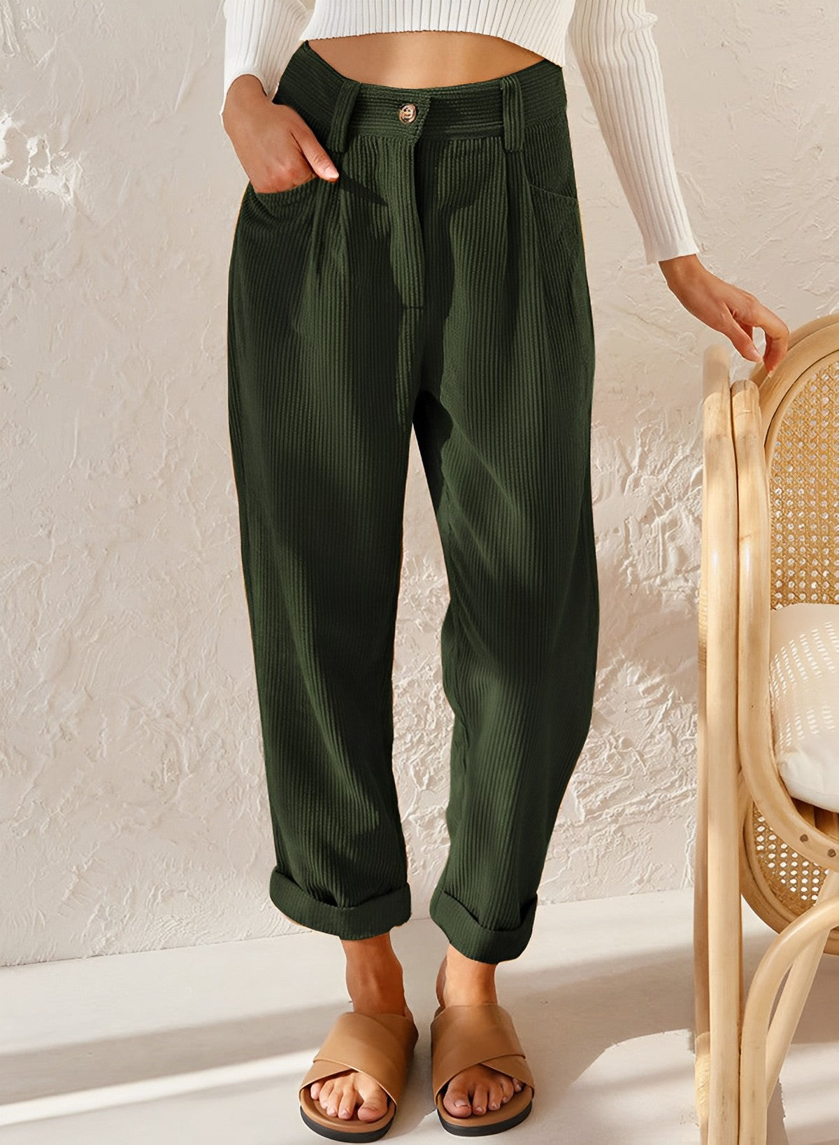 Pantalon vert foncé en tissu côtelé, coupe ample, porté par une femme. Mode décontractée, tendance automne, style confortable et élégant.