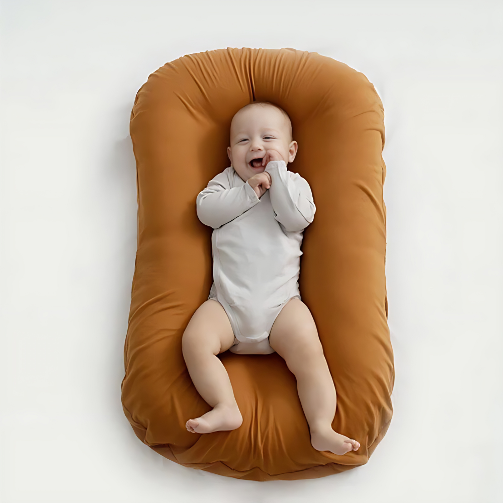 Bébé souriant allongé sur un coussin de maternité marron, vêtement blanc, confort et sécurité, accessoire essentiel pour nouveau-né.