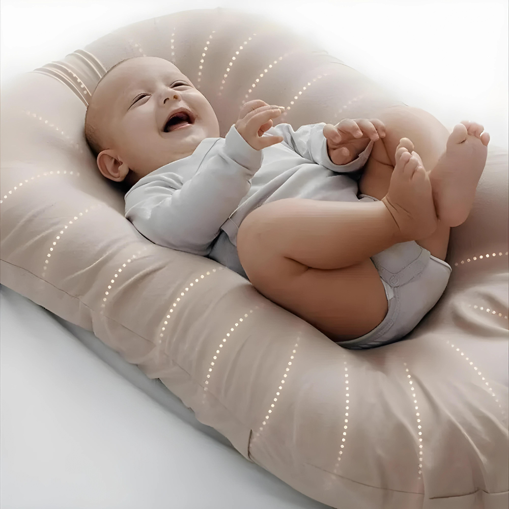 Bébé souriant allongé sur un coussin ergonomique beige, vêtement blanc, confort et sécurité, accessoire essentiel pour nouveau-né, maternité.