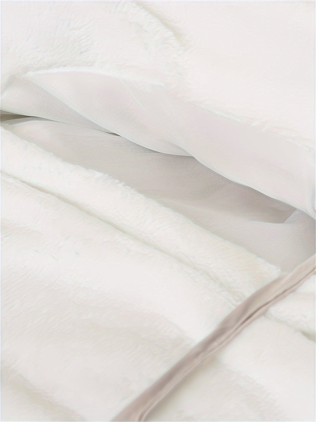 Couette blanche en tissu doux et moelleux, avec doublure en maille visible. Literie confortable, idéale pour chambre à coucher moderne et cosy.