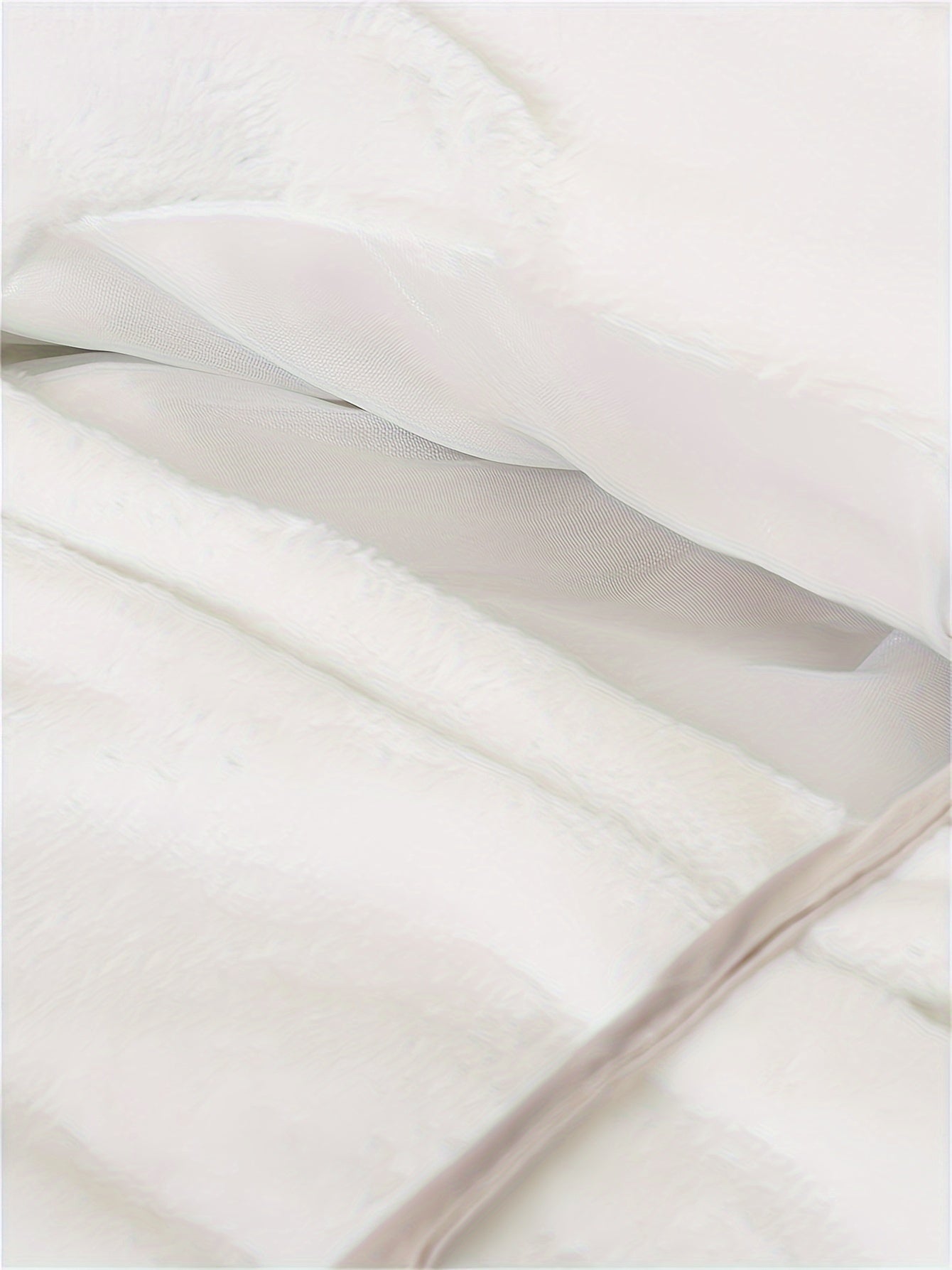 Couette blanche en tissu doux et moelleux, avec doublure en maille visible. Literie confortable, idéale pour chambre à coucher moderne et cosy.