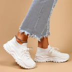 Jeans effilochés et baskets blanches tendance sur fond beige. Mode urbaine, chaussures confortables, style décontracté.
