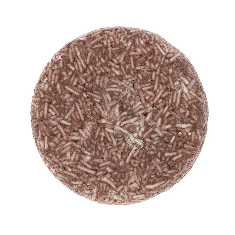 Shampoing solide rond marron avec texture granulée, zéro déchet, écologique, soin capillaire naturel, vue de dessus.