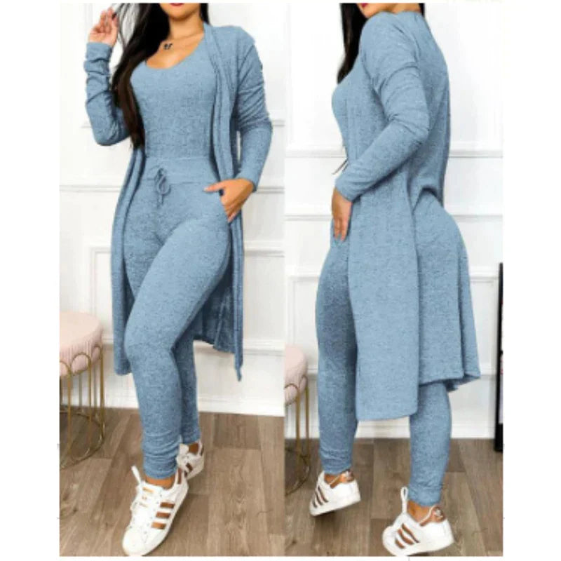 Combinaison femme bleu ciel avec cardigan long, tenue décontractée élégante, baskets blanches, mode féminine moderne, intérieur chic.