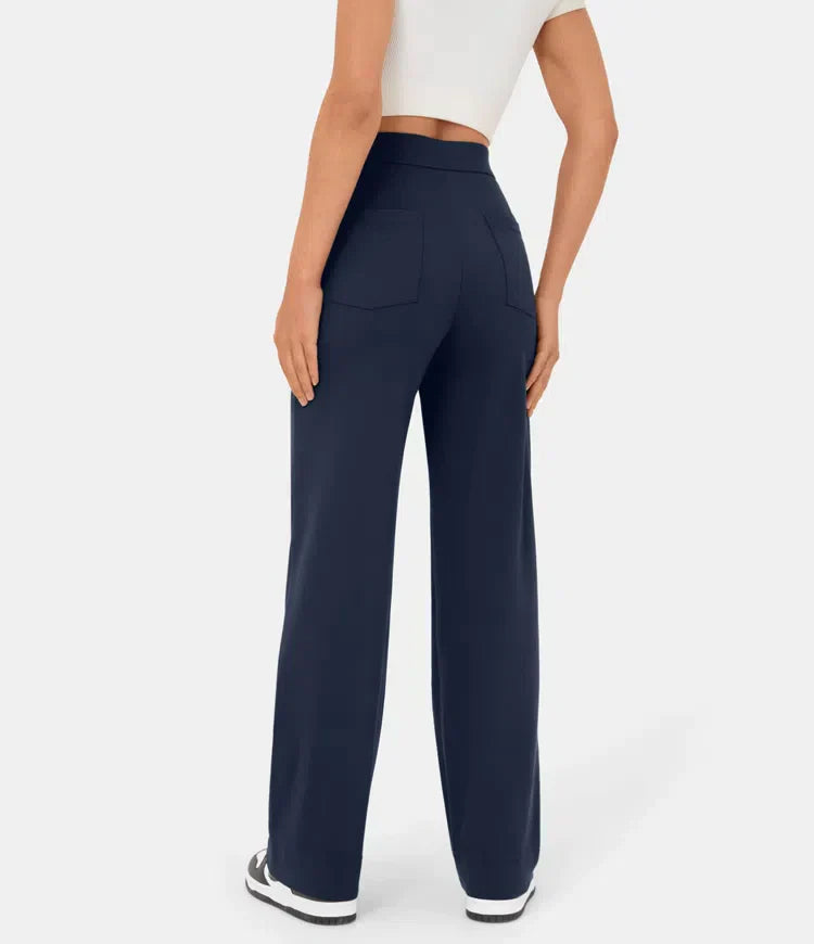 Femme portant un pantalon large bleu marine, taille haute, avec poches arrière, associé à un haut blanc court et des baskets noires.