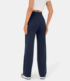 Femme portant un pantalon large bleu marine, taille haute, avec poches arrière, associé à un haut blanc court et des baskets noires.