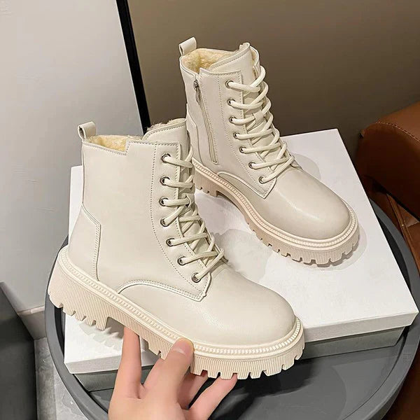 Bottes blanches en cuir avec lacets et semelles épaisses, posées sur une boîte. Chaussures tendance pour l'hiver, style urbain et moderne.