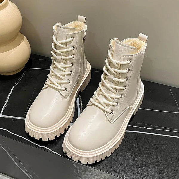 Bottes blanches en cuir avec lacets, semelle épaisse antidérapante, posées sur une surface noire. Chaussures tendance automne-hiver pour femmes.