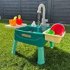 Table de jeu d'eau pour enfants sur pelouse, avec robinet, jouets colorés, seaux et accessoires. Idéal pour activités extérieures et jeux d'été.