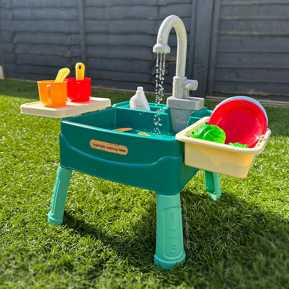 Table de jeu d'eau pour enfants sur pelouse, avec robinet, jouets colorés, seaux et accessoires. Idéal pour activités extérieures et jeux d'été.