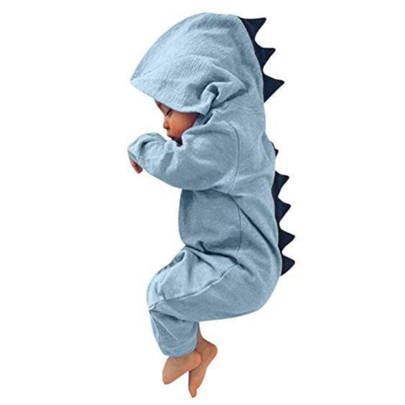 Bébé en combinaison dinosaure bleue avec capuche et crêtes noires, dormant paisiblement. Pyjama mignon, vêtement bébé, déguisement dinosaure.