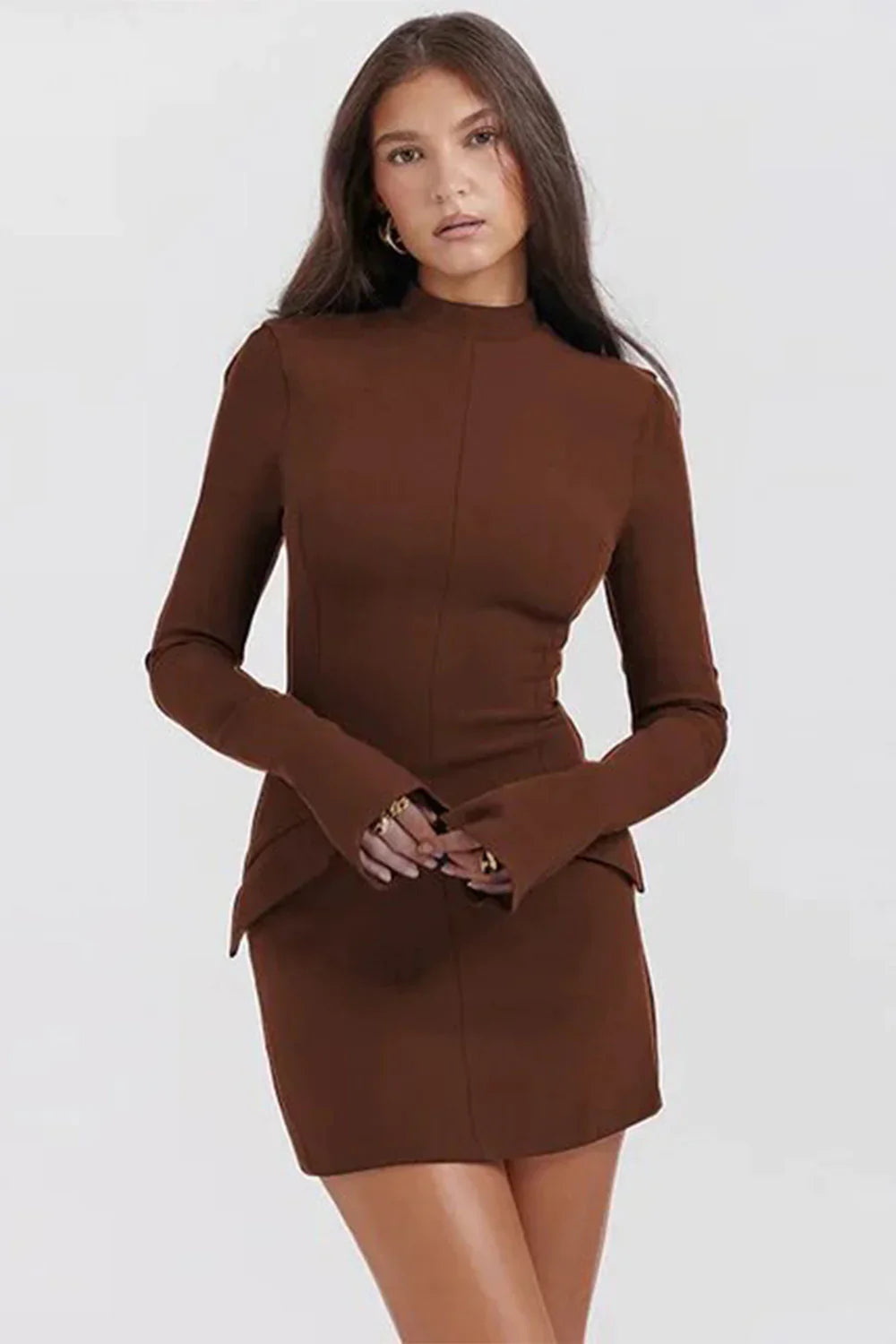 Femme portant une robe marron élégante à manches longues, style moderne et minimaliste, sur fond blanc. Mode féminine chic et tendance.