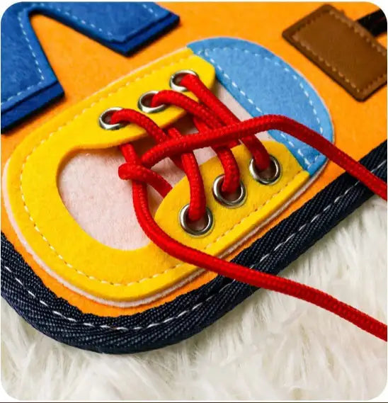 Chaussure éducative en feutrine colorée avec lacets rouges, jouet d'apprentissage pour enfants, développement de la motricité fine, sur tapis blanc.